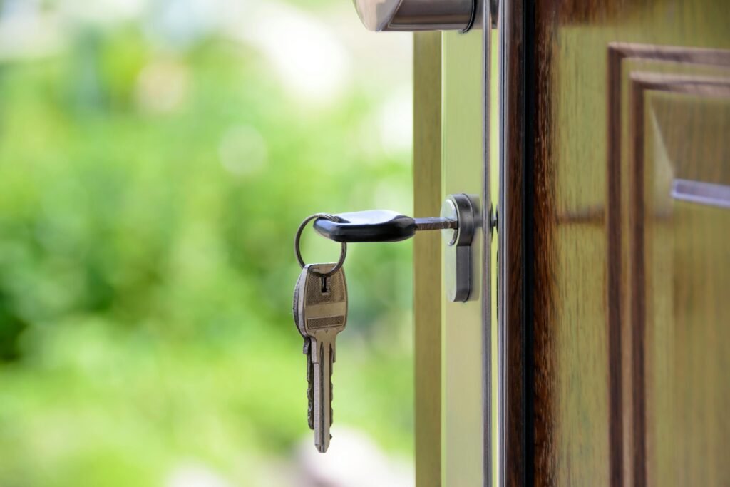 A set of keys hanging from the lock of an open door, suggesting the ownership of a house.